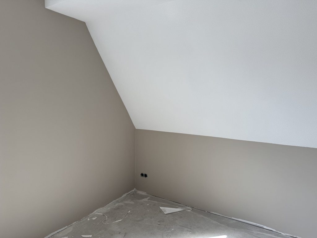 Zolderkamer met een schuine wand in wit en rechte wanden in een zachte zandkleur